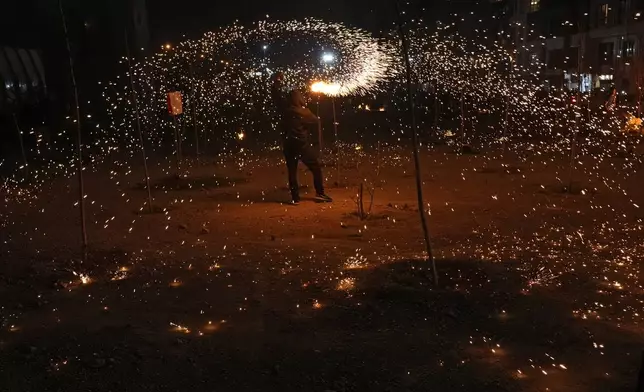 An Iranian man plays with a firework celebrating Chaharshanbe Souri, or Wednesday Feast, an ancient Festival of Fire on the eve of the last Wednesday of the Persian year, in Tehran, Iran, Tuesday, March 18, 2025. (AP Photo/Vahid Salemi)