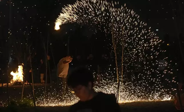 An Iranian man plays with a firework celebrating Chaharshanbe Souri, or Wednesday Feast, an ancient Festival of Fire on the eve of the last Wednesday of the Persian year, in Tehran, Iran, Tuesday, March 18, 2025. (AP Photo/Vahid Salemi)