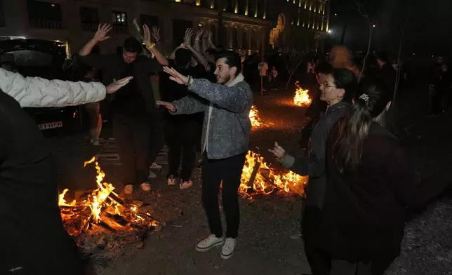 Iranians dance while celebrating Chaharshanbe Souri, or Wednesday Feast, an ancient Festival of Fire on the eve of the last Wednesday of the Persian year, in Tehran, Iran, Tuesday, March 18, 2025. (AP Photo/Vahid Salemi)