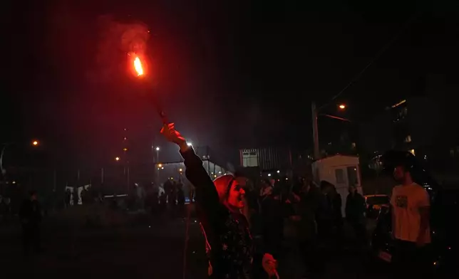 An Iranian woman holds up a firework celebrating Chaharshanbe Souri, or Wednesday Feast, an ancient Festival of Fire on the eve of the last Wednesday of the Persian year, in Tehran, Iran, Tuesday, March 18, 2025. (AP Photo/Vahid Salemi)