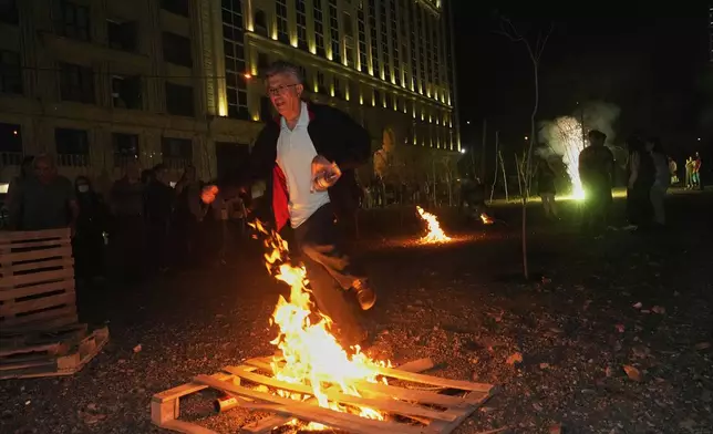 An Iranian man jumps over a bonfire celebrating Chaharshanbe Souri, or Wednesday Feast, an ancient Festival of Fire on the eve of the last Wednesday of the Persian year, in Tehran, Iran, Tuesday, March 18, 2025. (AP Photo/Vahid Salemi)