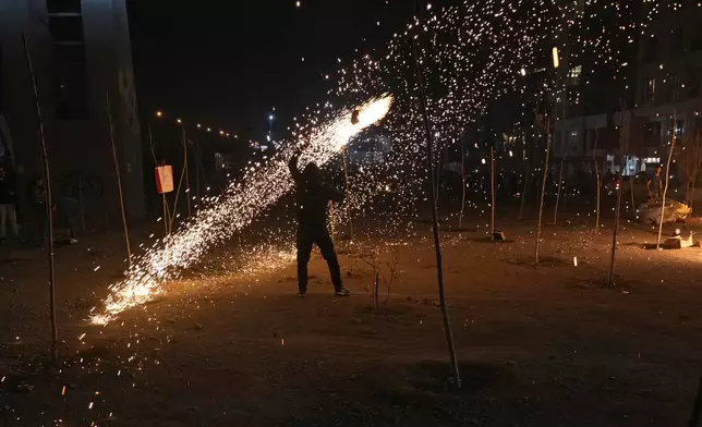 An Iranian man plays with a firework celebrating Chaharshanbe Souri, or Wednesday Feast, an ancient Festival of Fire on the eve of the last Wednesday of the Persian year, in Tehran, Iran, Tuesday, March 18, 2025. (AP Photo/Vahid Salemi)