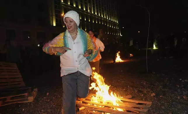 An Iranian woman jumps over a bonfire celebrating Chaharshanbe Souri, or Wednesday Feast, an ancient Festival of Fire on the eve of the last Wednesday of the Persian year, in Tehran, Iran, Tuesday, March 18, 2025. (AP Photo/Vahid Salemi)