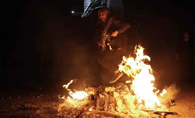 An Iranian woman jumps over a bonfire celebrating Chaharshanbe Souri, or Wednesday Feast, an ancient Festival of Fire on the eve of the last Wednesday of the Persian year, in Tehran, Iran, Tuesday, March 18, 2025. (AP Photo/Vahid Salemi)