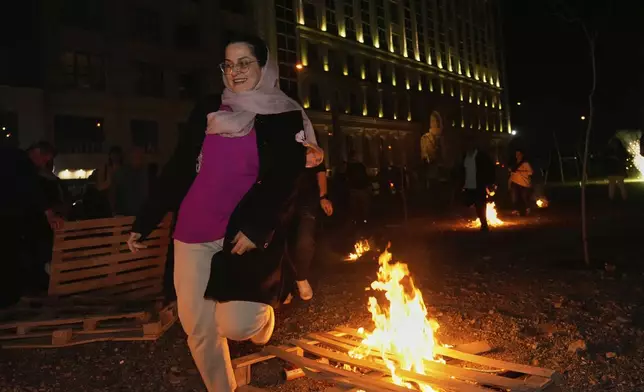 An Iranian woman jumps over a bonfire celebrating Chaharshanbe Souri, or Wednesday Feast, an ancient Festival of Fire on the eve of the last Wednesday of the Persian year, in Tehran, Iran, Tuesday, March 18, 2025. (AP Photo/Vahid Salemi)