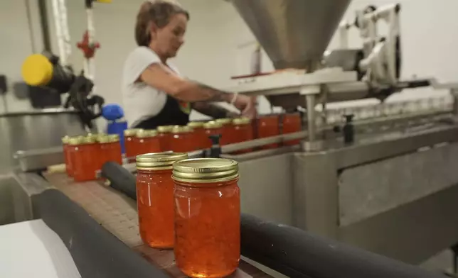 An employee at the Davidson of Dundee Citrus Candy and Jelly Factory, seals tangerine jelly containers, Tuesday, Feb. 18, 2025, in Lake Wales, Fla. (AP Photo/Marta Lavandier)