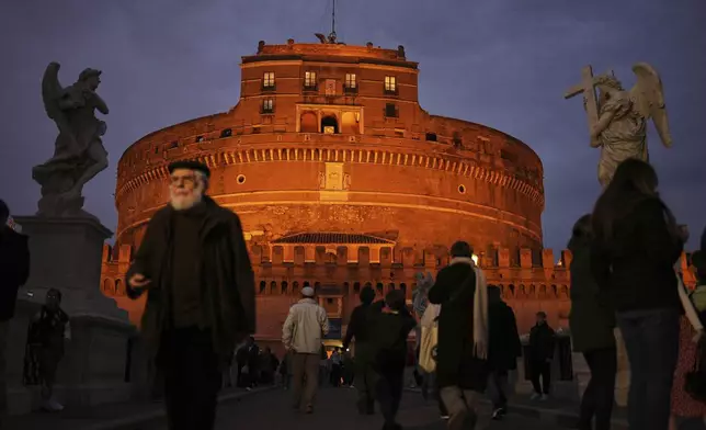 Locals and tourists walk outside the Sant'Angelo castle as the sun sets in Rome, Italy, Friday, March 7, 2025. (AP Photo/Francisco Seco)
