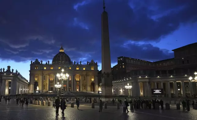 People walk at dusk in St Peter's Square at The Vatican, Thursday, Feb. 27, 2025. (AP Photo/Kirsty Wigglesworth)