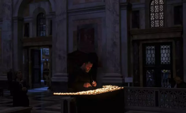 A man lights a candle inside the St. Paul's Outside The Walls Basilica in Rome, Wednesday, Feb. 26, 2025. (AP Photo/Bernat Armangue)