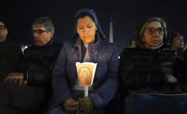 A woman holds a candle as Cardinal Robert Francis Prevost, Prefect of the Dicastery for Bishops, leads the recitation of the Holy Rosary for Pope Francis' health in St Peter's Square at the Vatican, Monday, March 3, 2025. (AP Photo/Kirsty Wigglesworth)