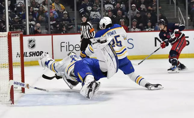 Buffalo Sabres' goaltender James Reimer (47) and Owen Power (25) make a save on a shot by Winnipeg Jets' Mark Scheifele (55) during the second period of an NHL hockey game in Winnipeg, Manitoba, Sunday March 23, 2025. (Fred Greenslade/The Canadian Press via AP)