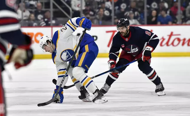Buffalo Sabres' Jack Quinn (22) settles down a bouncing puck in front of Winnipeg Jets' Dylan Demelo (2) during the second period of an NHL hockey game in Winnipeg, Manitoba, Sunday March 23, 2025. (Fred Greenslade/The Canadian Press via AP)