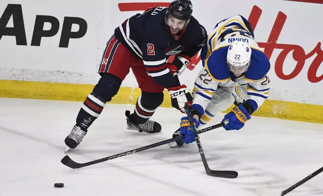 Buffalo Sabres' Jack Quinn (22) and Winnipeg Jets' Dylan Demelo (2) battle for the puck during the first period of an NHL hockey game in Winnipeg, Manitoba, Sunday March 23, 2025. (Fred Greenslade/The Canadian Press via AP)