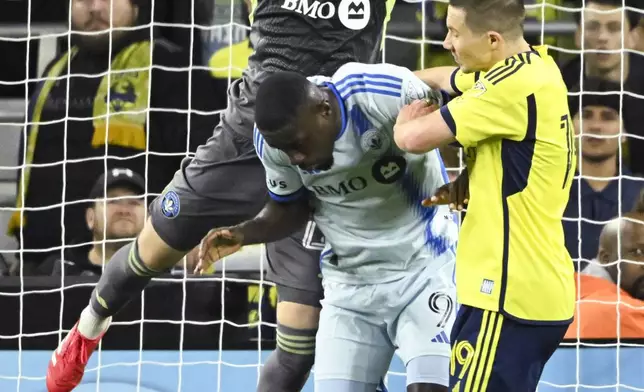 CF Montréal goalkeeper Jonathan Sirois, top, makes a save in front of CF Montréal forward Prince Osei Owusu (9) and Nashville SC midfielder Alex Muyl (19) during the first half of an MLS soccer match Saturday, March 22, 2025, in Nashville, Tenn. (AP Photo/John Amis)