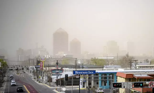 Travel is highly discouraged in the #ABQ metro through Tuesday afternoon, March 18, 2025, due to visibility below a quarter mile from blowing dust and dangerous crosswinds of up to 70 mph on north to south roads and highways, in downtown Albuquerque, N.M., looking west from Route 66. (AP Photo/Roberto E. Rosales)