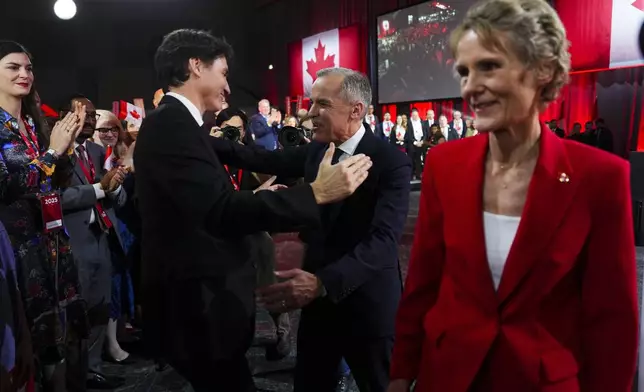 Liberal Party of Canada Leader Mark Carney, center right, speaks to Canada's Prime Minister Justin Trudeau after Carney was announced as the winner of the party leadership at the announcement event in Ottawa, Ontario, Sunday, March 9, 2025. (Sean Kilpatrick/The Canadian Press via AP)