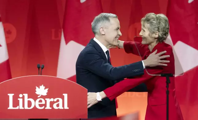 Newly appointed Liberal Leader Mark Carney hugs his wife Diana Fox Carney following his speech at the Liberal leadership announcement in Ottawa, Ontario, Sunday, March 9, 2025. (Adrian Wyld/The Canadian Press via AP)