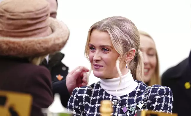Charlotte Giles, right, girlfriend of the late Michael O'Sullivan speaks with Britain's Queen Camilla after the BetMGM Queen Mother Champion Chase on day two of the 2025 Cheltenham Festival at Cheltenham Racecourse, England, Wednesday, March 12, 2025. (Mike Egerton/PA via AP)