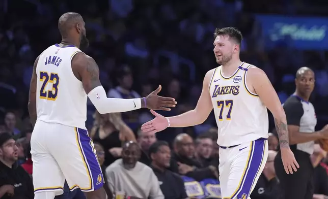 Los Angeles Lakers forward LeBron James, left, and guard Luka Doncic slap hands as Doncic comes out of the game and James comes in during the second half of an NBA basketball game against the Los Angeles Clippers, Sunday, March 2, 2025, in Los Angeles. (AP Photo/Mark J. Terrill)