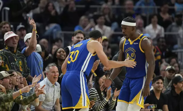 Golden State Warriors forward Jimmy Butler III, right, celebrates with guard Stephen Curry (30) after scoring during the first half of an NBA basketball game against the Dallas Mavericks, Sunday, Feb. 23, 2025, in San Francisco. (AP Photo/Godofredo A. Vásquez)