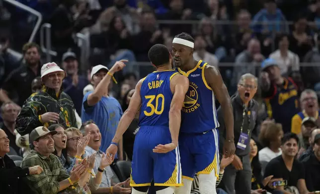 Golden State Warriors forward Jimmy Butler III, right, celebrates with guard Stephen Curry (30) after scoring during the first half of an NBA basketball game against the Dallas Mavericks, Sunday, Feb. 23, 2025, in San Francisco. (AP Photo/Godofredo A. Vásquez)