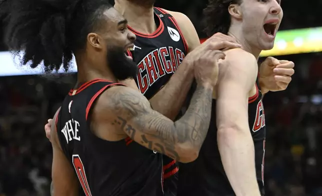 Chicago Bulls' Josh Giddey right, celebrates with teammates Nikola Vucevic center, and Coby White left, after making the winning basket against the Los Angeles Lakers in an NBA basketball game Thursday, March 27, 2025, in Chicago. (AP Photo/Paul Beaty)