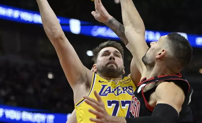 Los Angeles Lakers' Luka Doncic (77) goes up for a shot against Chicago Bulls' Nikola Vucevic (9) and Kevin Huerter (13) during the first half of an NBA basketball game Thursday, March 27, 2025, in Chicago. (AP Photo/Paul Beaty)