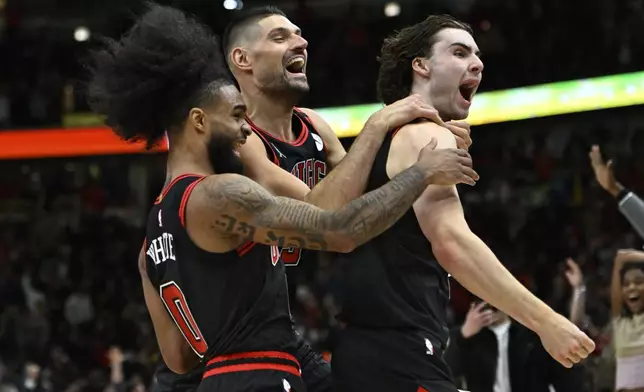 Chicago Bulls' Josh Giddey right, celebrates with teammates Nikola Vucevic center, and Coby White left, after making the winning basket against the Los Angeles Lakers in an NBA basketball game Thursday, March 27, 2025, in Chicago. (AP Photo/Paul Beaty)