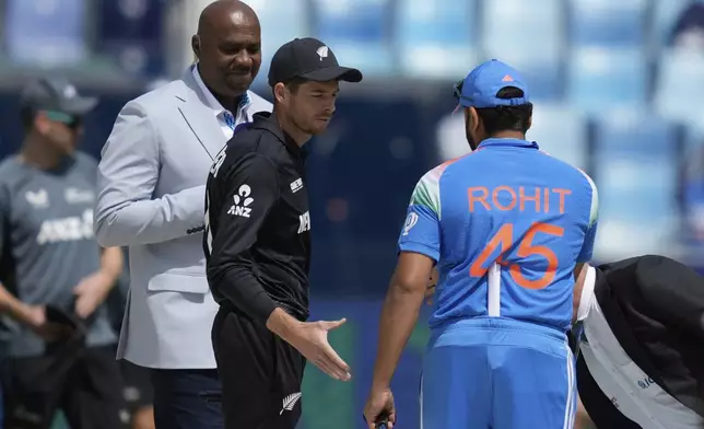 New Zealand's captain Mitch Santner, center, greets India's captain Rohit Sharma after the coin toss ahead of the ICC Champions Trophy cricket match between India and New Zealand at Dubai International Cricket Stadium in Dubai, United Arab Emirates, Sunday, March 2, 2025. (AP Photo/Altaf Qadri)