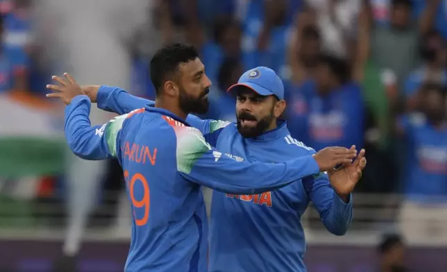India's Varun Chakravarthy, left, celebrate the wicket of New Zealand's Will Young with India's Virat Kohli, right, during the ICC Champions Trophy cricket match between India and New Zealand at Dubai International Cricket Stadium in Dubai, United Arab Emirates, Sunday, March 2, 2025. (AP Photo/Altaf Qadri )
