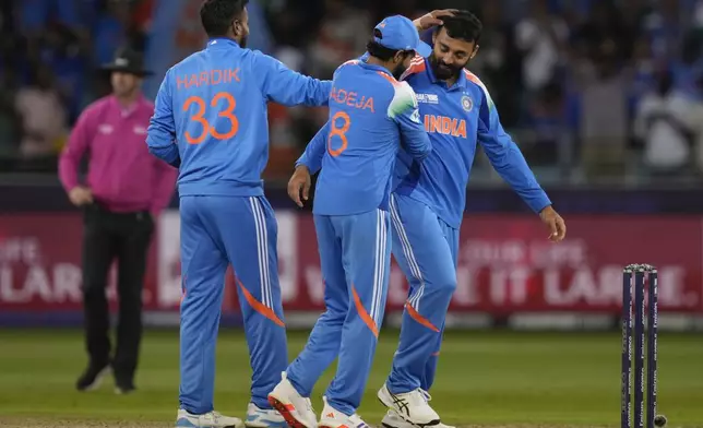 India's Varun Chakravarthy, right, celebrate the wicket of New Zealand's Matt Henry during the ICC Champions Trophy cricket match between India and New Zealand at Dubai International Cricket Stadium in Dubai, United Arab Emirates, Sunday, March 2, 2025. (AP Photo/Altaf Qadri )