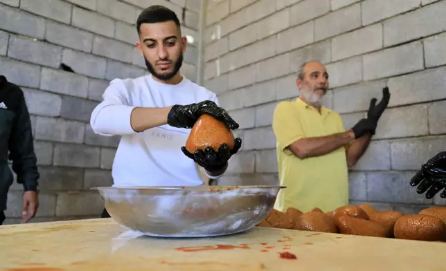 Libyan volunteers serve traditional unleavened Libyan bread made out of barley in Tajoura, east of Libya's capital Tripoli, Tuesday, March 11, 2025, during the Muslim holy month of Ramadan. (AP Photo/Yousef Murad)