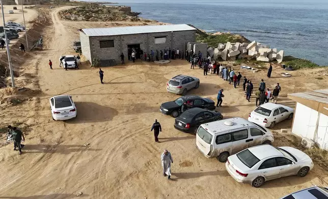 Libyan volunteers serve free traditional unleavened Libyan bread made out of barley for passing fasting people in Tajoura, east of Libya's capital Tripoli, Tuesday, March 11, 2025, during the Muslim holy month of Ramadan. (AP Photo/Yousef Murad)