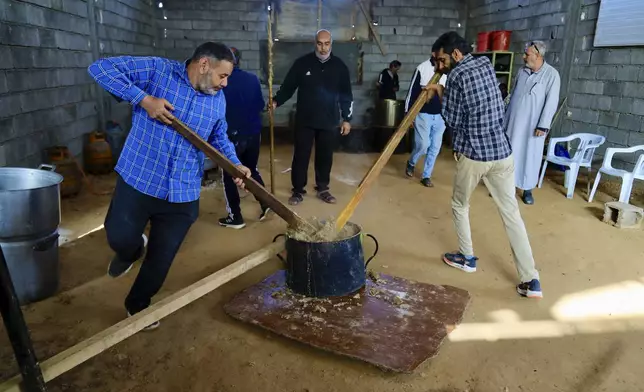 Libyan volunteers mixes the products to make traditional unleavened Libyan bread made out of barley in Tajoura, east of Libya's capital Tripoli, Tuesday, March 11, 2025, during the Muslim holy month of Ramadan. (AP Photo/Yousef Murad)