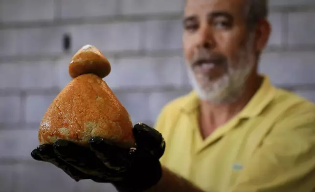 A Libyan volunteer shows a just made traditional unleavened Libyan bread made out of barley in Tajoura, east of Libya's capital Tripoli, Tuesday, March 11, 2025, during the Muslim holy month of Ramadan. (AP Photo/Yousef Murad)