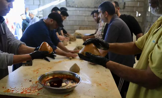 Libyan volunteers serve traditional unleavened Libyan bread made out of barley in Tajoura, east of Libya's capital Tripoli, Tuesday, March 11, 2025, during the Muslim holy month of Ramadan. (AP Photo/Yousef Murad)