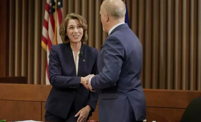 Wisconsin Supreme Court candidates Brad Schimel and Susan Crawford shake hands after a debate Wednesday, March 12, 2025, in Milwaukee. (AP Photo/Morry Gash)