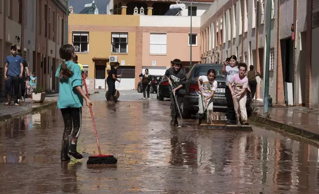 Residents clear mud from the streets after heavy rains in Campanillas, Malaga, Spain, Tuesday, March 18, 2025. (AP Photo/Gregorio Marrero)