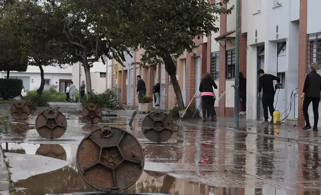 Residents clear mud from the streets after heavy rains in Campanillas, Malaga, Spain, Tuesday, March 18, 2025. (AP Photo/Gregorio Marrero)