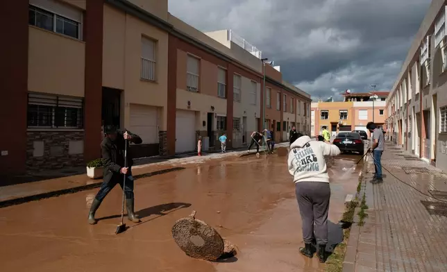 Residents clear mud from the streets after heavy rains in Campanillas, Malaga, Spain, Tuesday, March 18, 2025. (AP Photo/Gregorio Marrero)