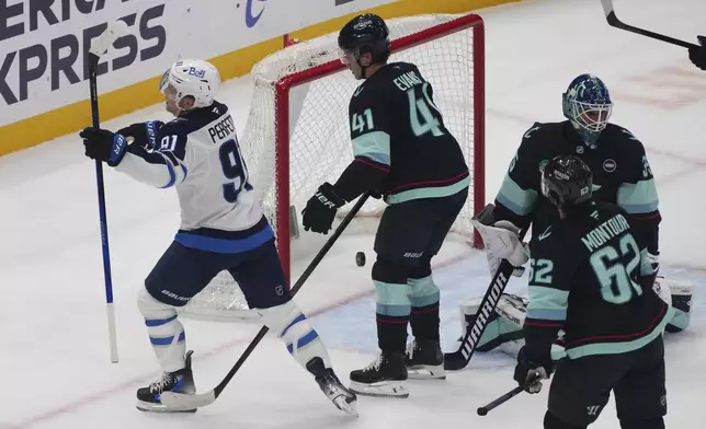 Winnipeg Jets center Cole Perfetti (91) reacts to scoring a goal against Seattle Kraken goaltender Joey Daccord, right, as defenseman Ryker Evans (41) and defenseman Brandon Montour (62) look on during the first period of an NHL hockey game Sunday, March 16, 2025, in Seattle. (AP Photo/Lindsey Wasson)