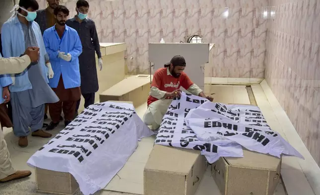 Rescue workers gather around coffins containing the bodies of victims following a train attack upon arrival at a hospital in Quetta, Pakistan's southwestern Balochistan province, Thursday March 13, 2025. (AP Photo/Arshad Butt)