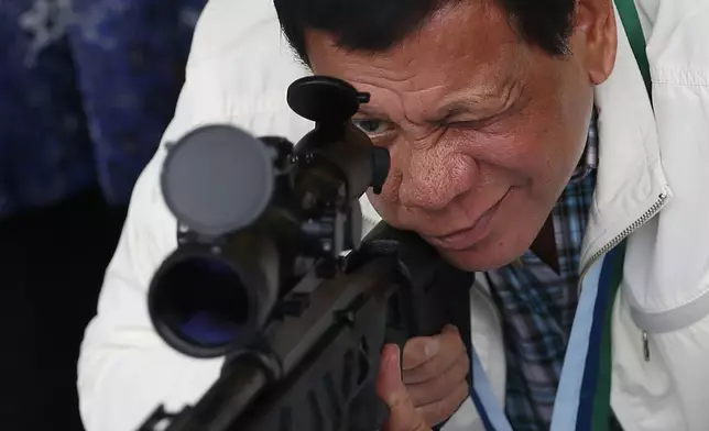 FILE - Philippine President Rodrigo Duterte checks the scope of a Chinese-made CS/LR4A sniper rifle during the presentation of thousands of rifles and ammunition by China to the Philippines at Clark Airbase in northern Philippines on June 28, 2017. (AP Photo/Bullit Marquez, File)