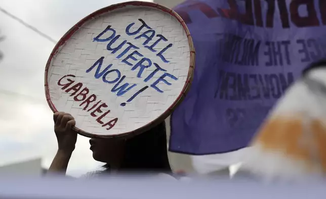 A person holds a sign against former Philippine President Rodrigo Duterte following his arrest in Quezon City, Philippines, Tuesday, March 11, 2025. (AP Photo/Basilio Sepe)