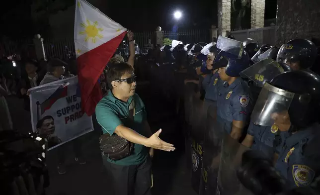 Supporters of former Philippine President Rodrigo Duterte stand in front of police as they gather outside the Villamor Air Base in Manila, Philippines, Tuesday, March 11, 2025. (AP Photo/Basilio Sepe)