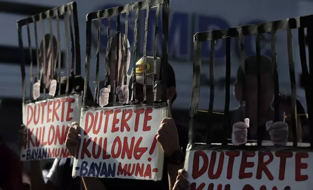 People hold signs against former Philippine President Rodrigo Duterte following his arrest in Quezon City, Philippines, Tuesday, March 11, 2025. (AP Photo/Basilio Sepe)