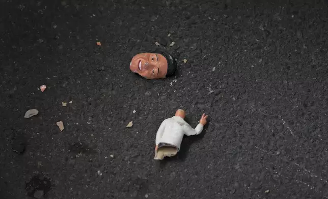 A broken doll bearing the face of Philippine President Ferdinand Marcos Jr. lies on the ground as supporters of former Philippine President Rodrigo Duterte hold a rally outside Villamor airbase after Duterte was arrested, Tuesday, March 11, 2025, near Manila, Philippines. (AP Photo/Aaron Favila)