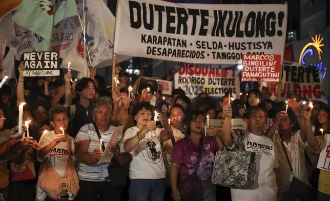 Relatives of victims of drug war and extrajudicial killings and activists hold signs and light candles during a protest against former Philippine President Rodrigo Duterte following his arrest in Quezon City, Philippines, Tuesday, March 11, 2025. (AP Photo/Basilio Sepe)