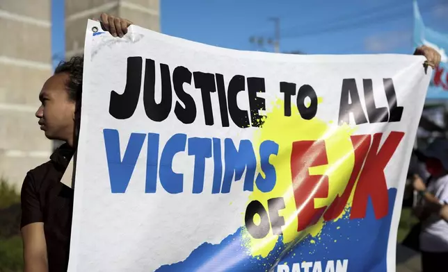 People hold a banner against former Philippine President Rodrigo Duterte following his arrest in Quezon City, Philippines, Tuesday, March 11, 2025. (AP Photo/Basilio Sepe)