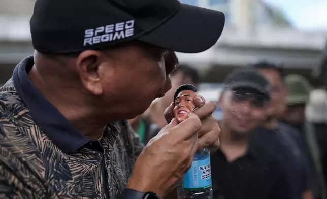 A supporter of former Philippine President Rodrigo Duterte spits on a doll bearing the face of Philippine President Ferdinand Marcos Jr. as they hold a rally outside Villamor airbase after Duterte was arrested, Tuesday, March 11, 2025, near Manila, Philippines. (AP Photo/Aaron Favila)